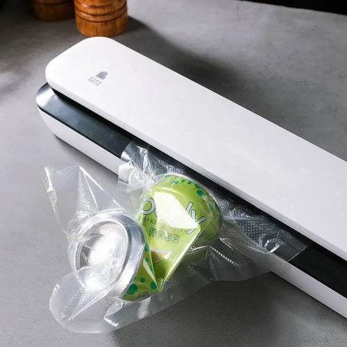 White vacuum sealing machine with vacuum-sealed bag containing a green produce pack