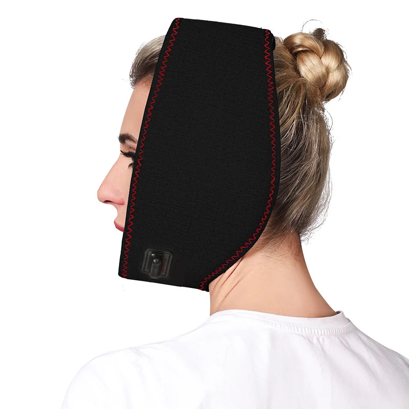 A woman wears a black, fabric jaw heating pad with red zig-zag stitching and a power control button.