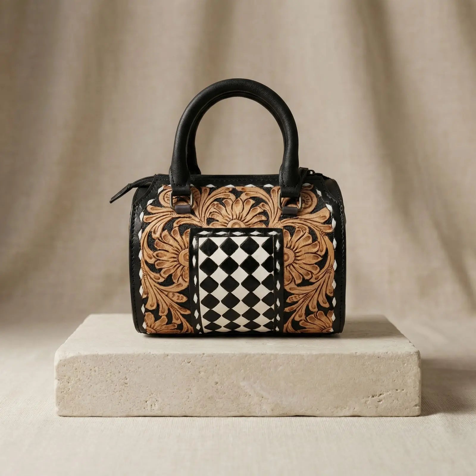 Luxury leather weekender trunk with hand-tooled floral carvings and a black and white checkered center panel.
