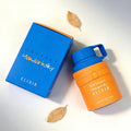 Odyssey Mandarin Sky Elixir perfume in a blue box and a cylindrical bottle with an orange leather-like sleeve.
