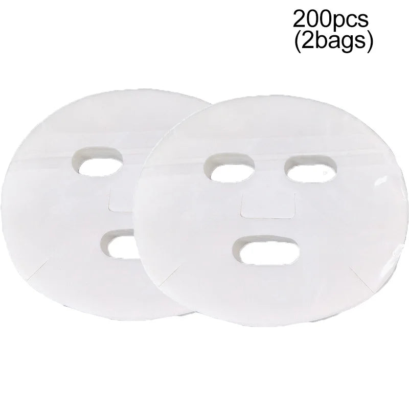 Two round, white, thin, disposable facial mask sheets with cutouts for eyes and mouth.