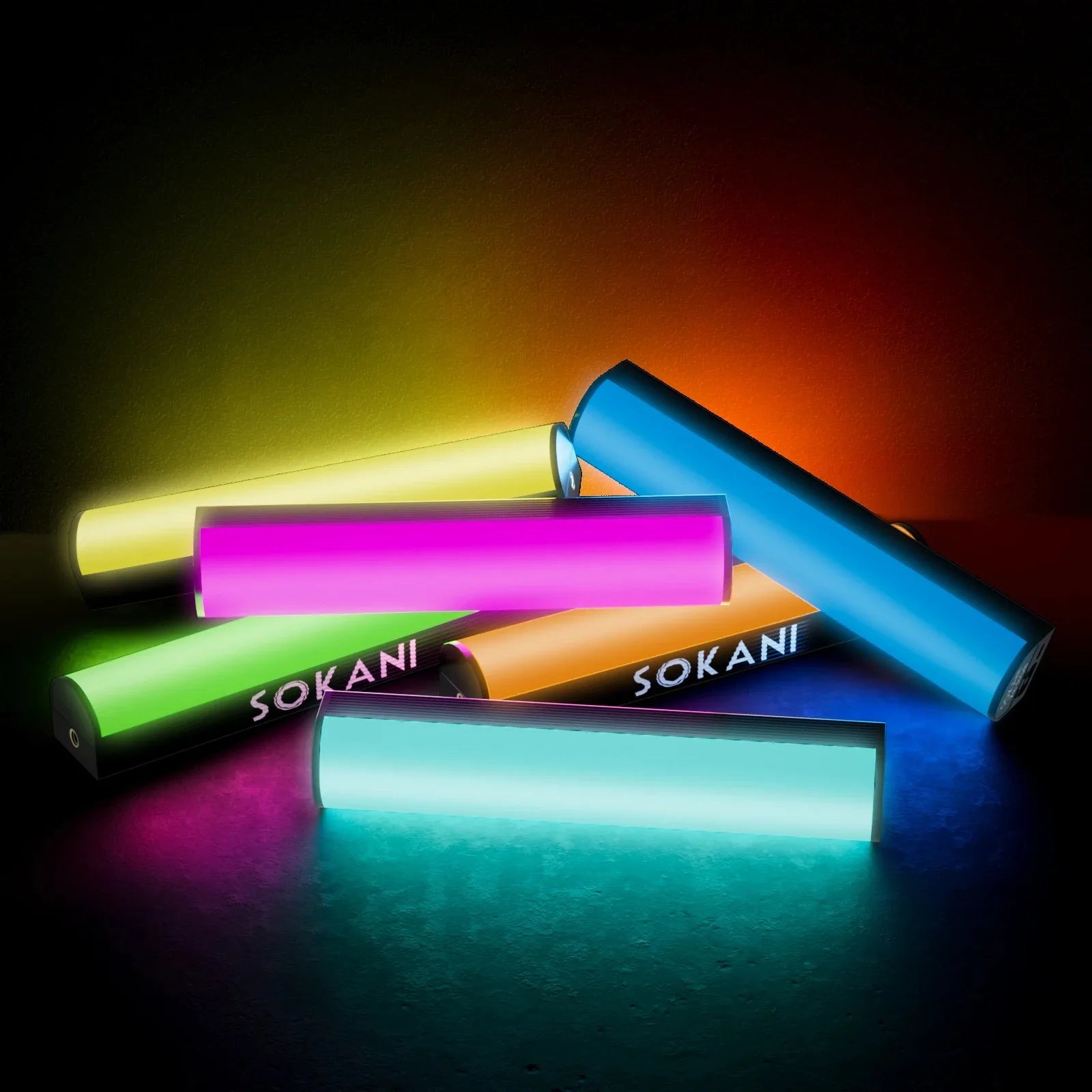 Pile of cylindrical LED light bars glowing in various colors for photography and video lighting.