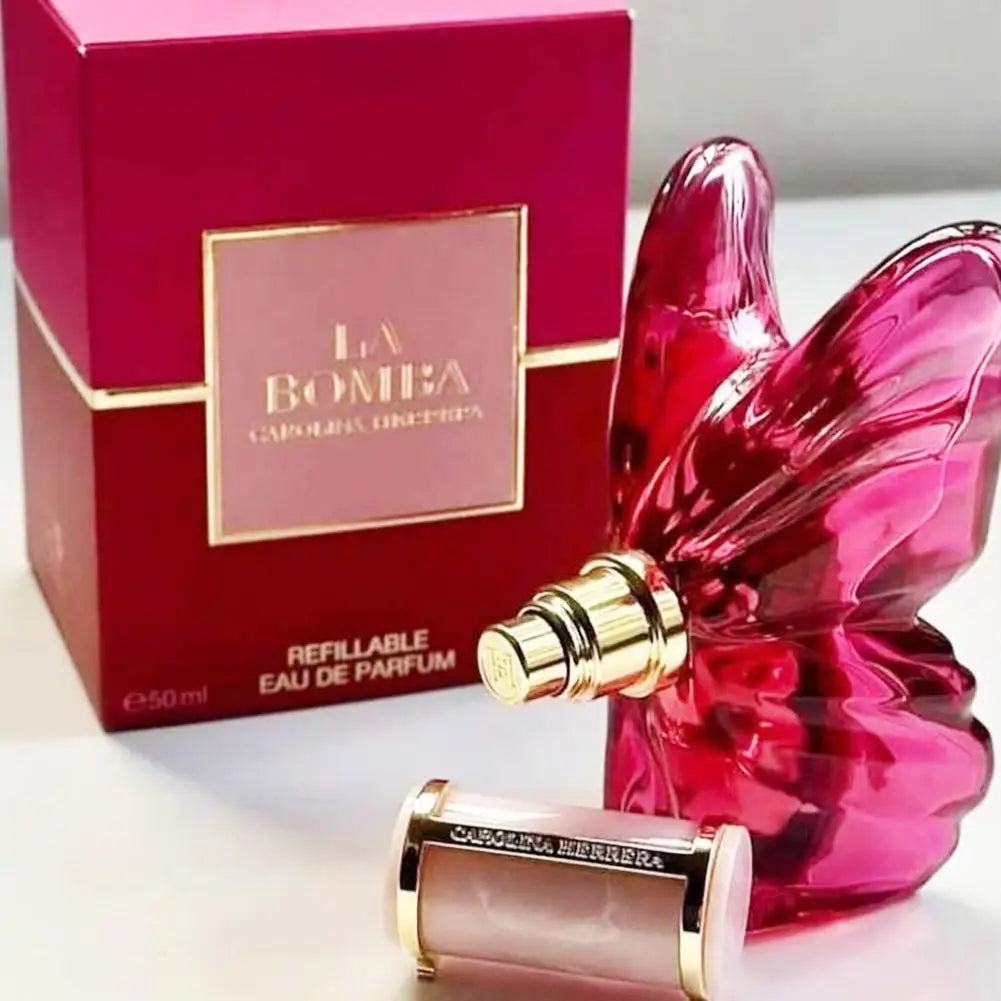 La Bomba 50ml refillable eau de parfum in a butterfly-shaped magenta glass bottle with its matching box.