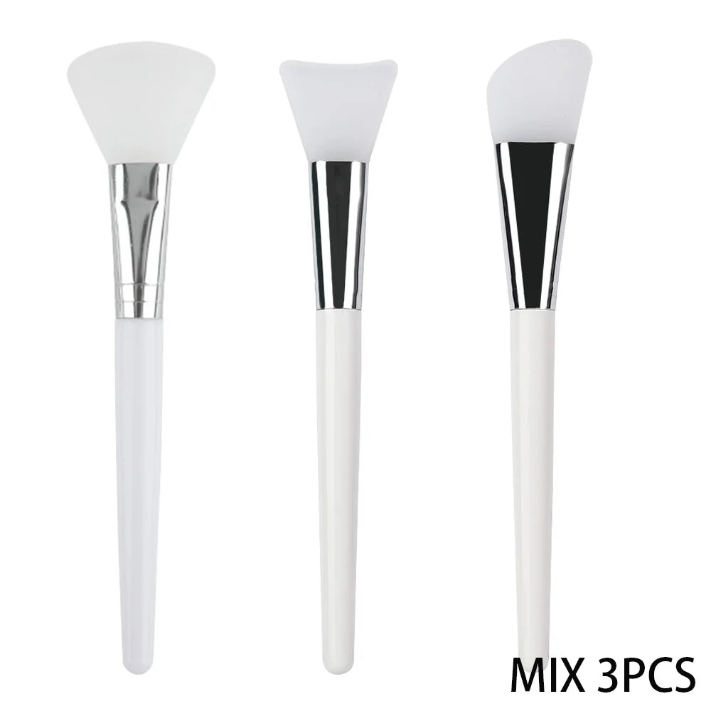 Three white silicone face mask brushes with silver ferrules and white handles, featuring different head shapes.