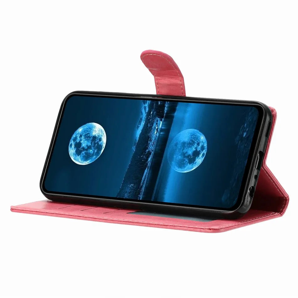 Pink leather wallet phone case with a magnetic strap, propped in landscape mode to display a moonlit screen.
