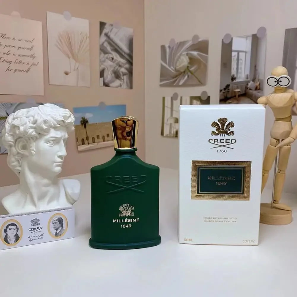 Creed Millésime 1849 unisex Eau de Parfum: green bottle with gold cap, box, and branding in a desk decor setting.