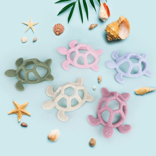Colorful turtle-shaped silicone teething toys for baby relief on blue background with sea shells.