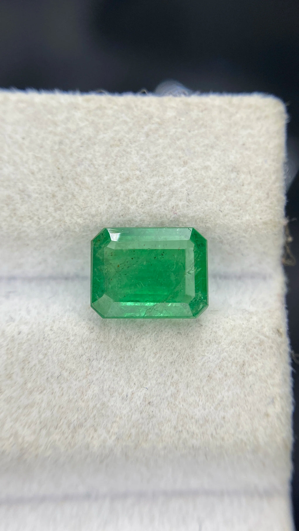 Green octagon emerald-cut emerald gemstone on white velvet