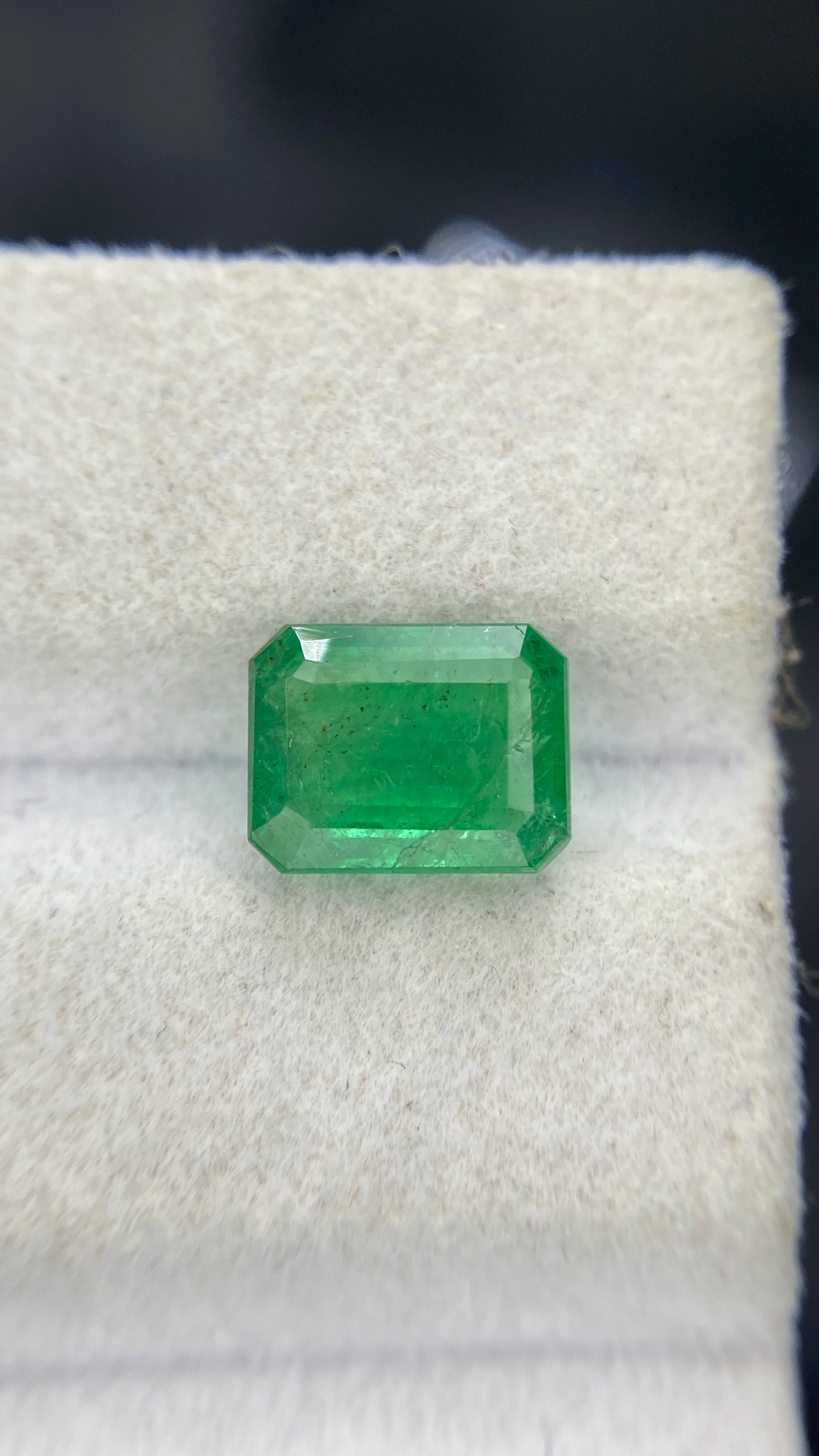 Green octagon emerald-cut emerald gemstone on white velvet