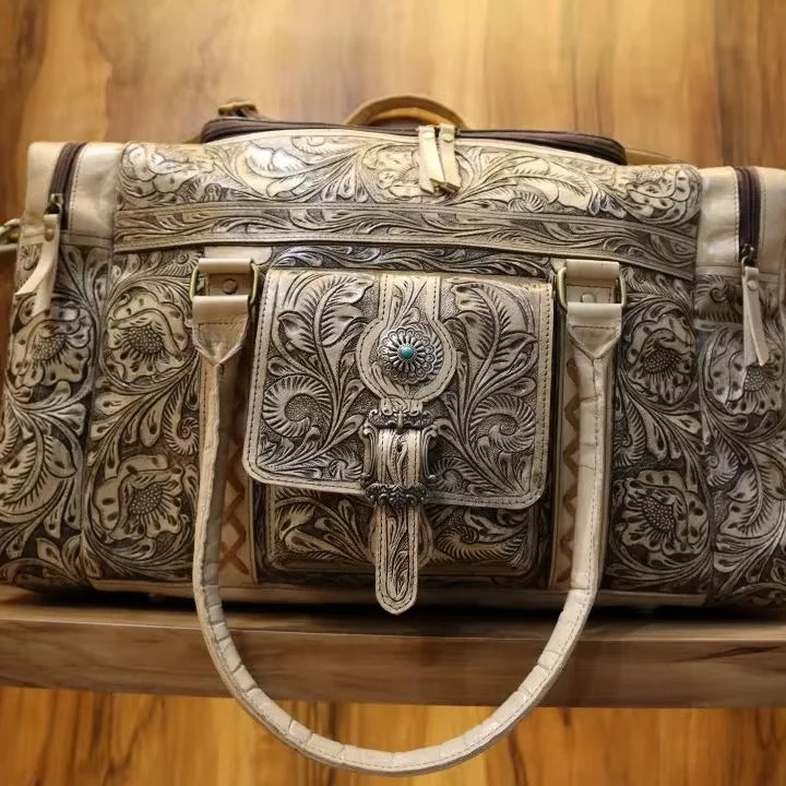 Vintage brown handmade cowhide weekender duffel bag with intricate Western floral tooling and turquoise stone detail.