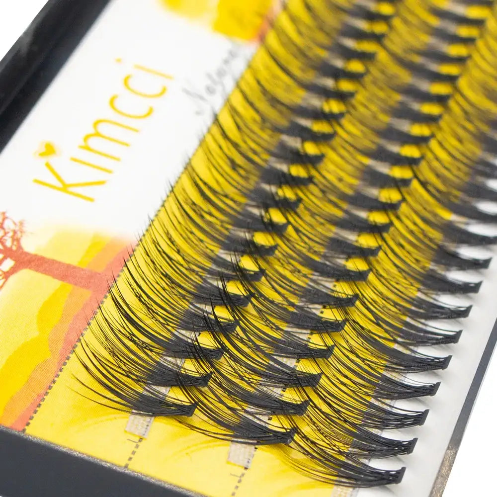 Black individual mink eyelash extension clusters arranged in a row on a yellow Kimcci branded tray.