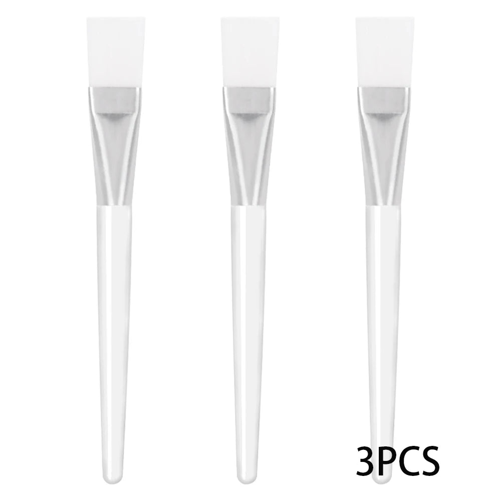 Three facial mask brushes with flat, flexible white silicone tips, silver ferrules, and translucent white handles.
