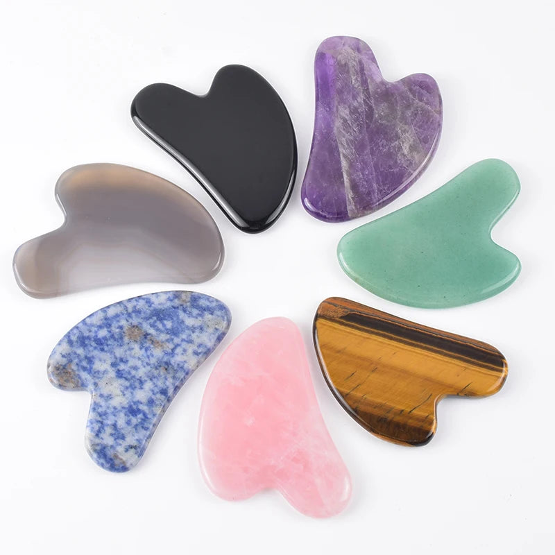 Assorted heart-shaped facial gua sha tools made from various polished natural stones in different colors and patterns.