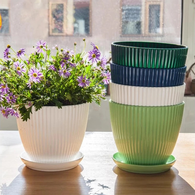 Stacked ribbed plastic planters with trays, blue top and green body, with blooms