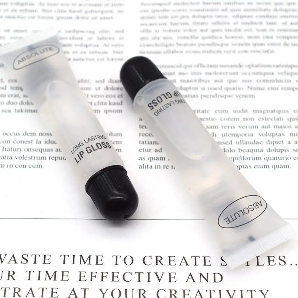 Two clear, long-lasting Absolute lip gloss tubes with black caps on a paper background for hydrating, plumping makeup.