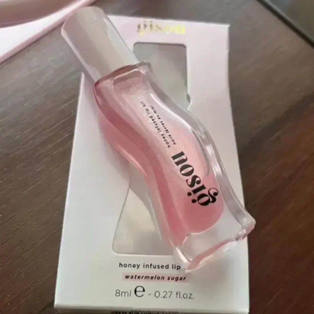 Gisou Honey Infused Lip Oil in Watermelon Sugar, pink moisturizing lip treatment in a clear bottle on white packaging.
