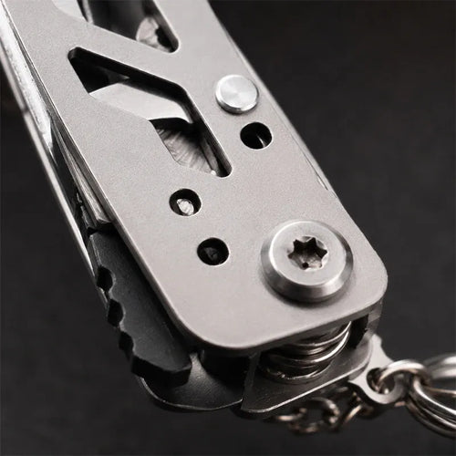 Silver multi-tool plier head with screw mechanism and keychain ring, close-up
