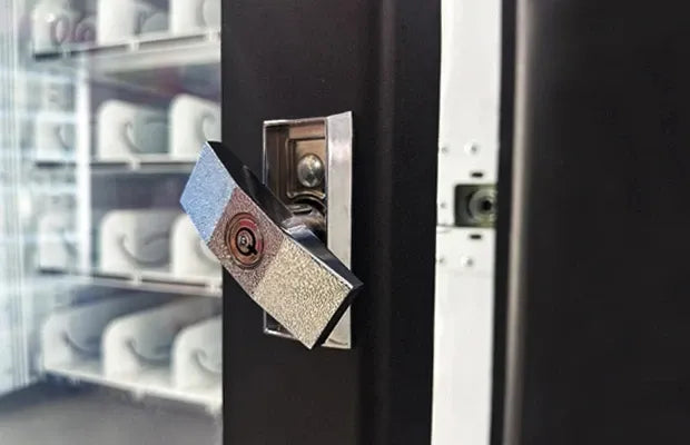 Vending machine door latch lock with metal strike plate