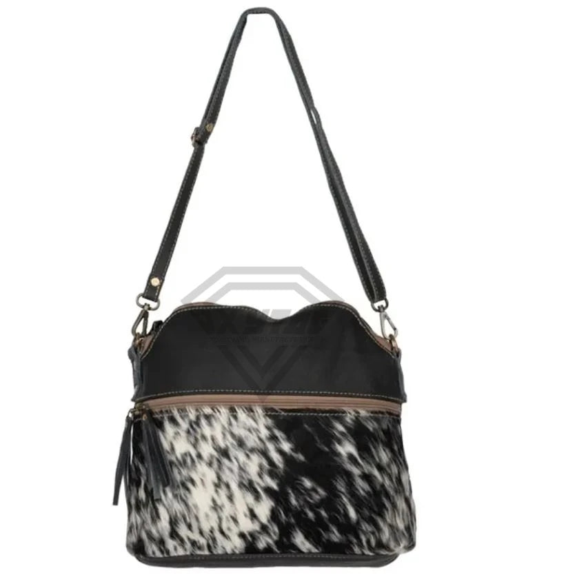 Luxury handmade crossbody bag in black leather and white-black cowhide hair-on print with adjustable shoulder strap.