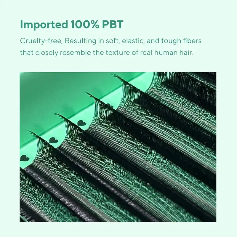 Close-up of fluffy black U-shaped premade eyelash extension fans on a green tray with small heart icons.