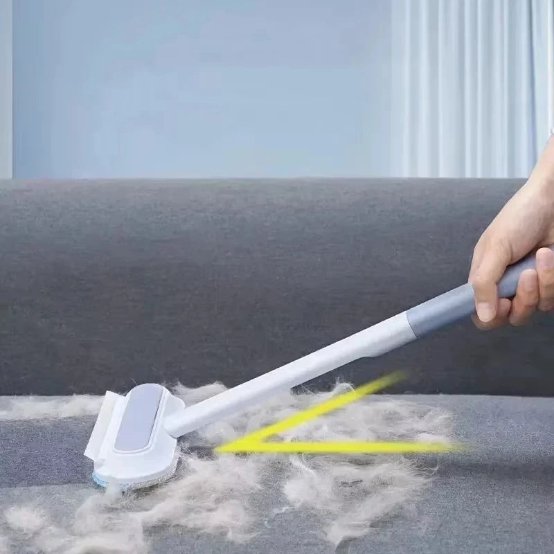 Manual long-handle pet hair remover brush effectively cleaning dog and cat fur from grey sofa upholstery.