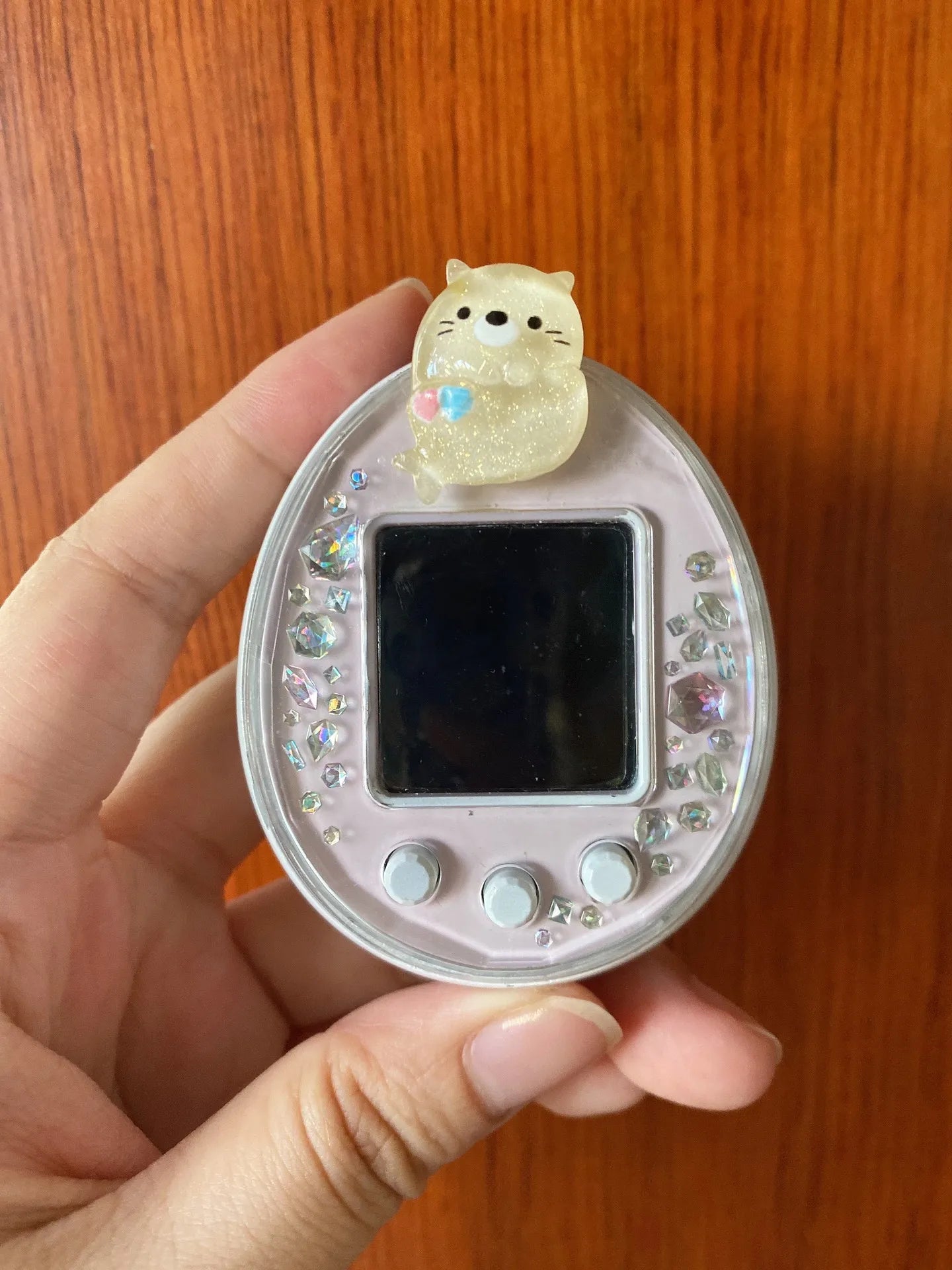 Tamagotchi Uni pink electronic pet case with sparkly silicone cat dust plug for scratch protection and cute style.