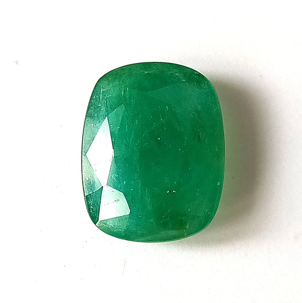 Green oval emerald gemstone, faceted front view with visible surface inclusions.