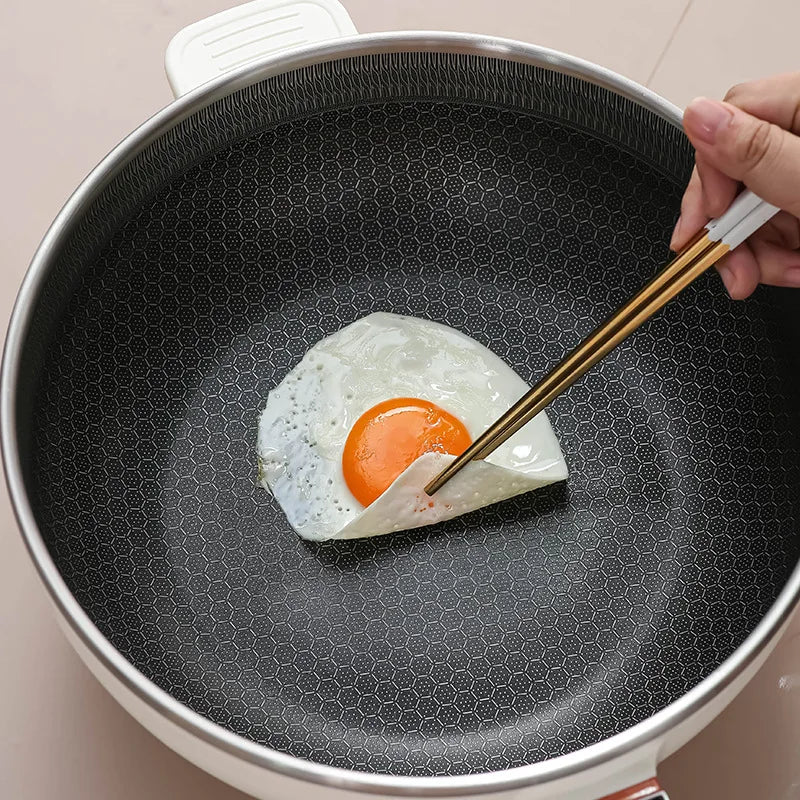 Electric nonstick frying pot interior with egg cooking, dark textured pan surface and white rim