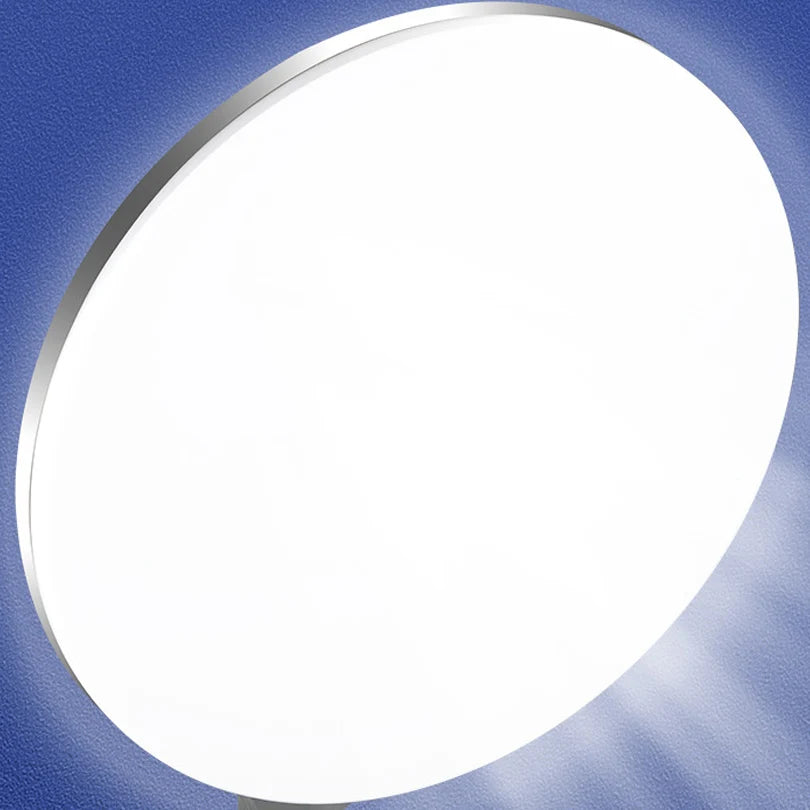 Round white LED flush mount ceiling light with a slim silver rim, emitting bright ambient light against a blue