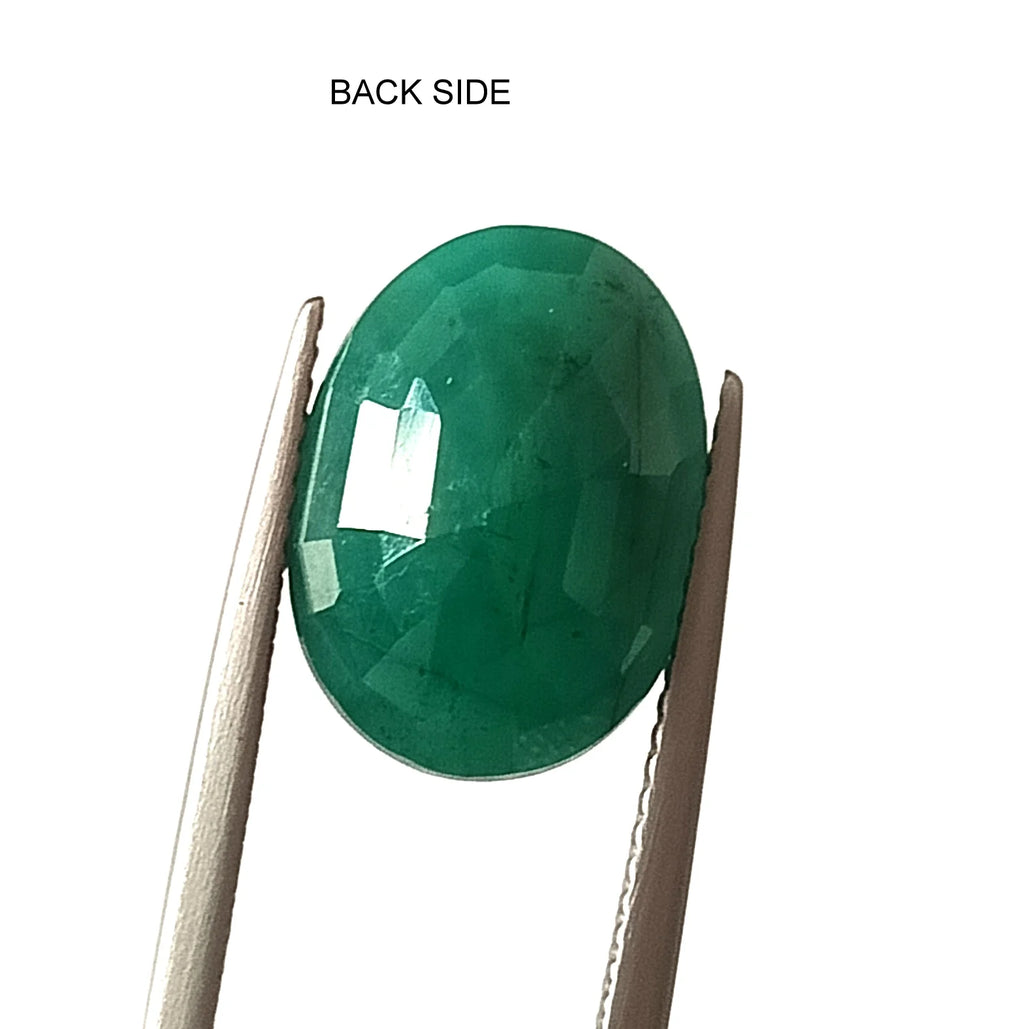 Oval green emerald gemstone, back side view with faceted surface reflections