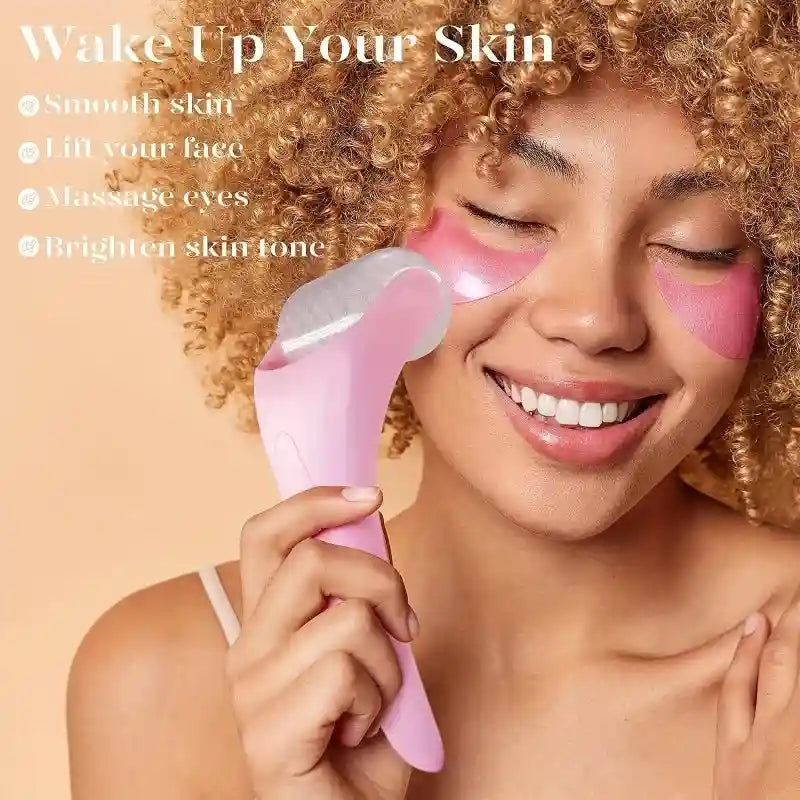 A person with curly hair using a pink handheld facial ice roller with a translucent barrel on their cheek.