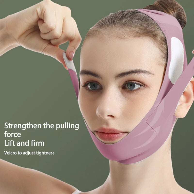 A person wears a pink, reusable V-line face slimming bandage with adjustable Velcro straps to lift the chin and cheeks.