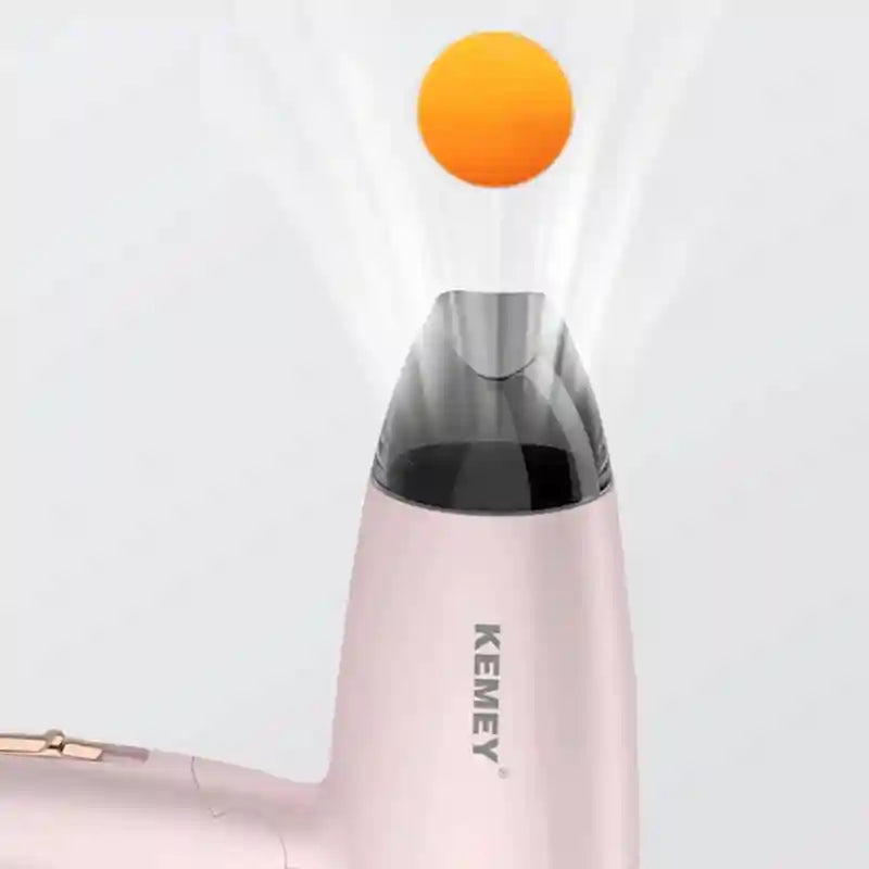 Pink Kemei compact foldable hair dryer with concentrator nozzle, demonstrating powerful airflow for travel and home use.