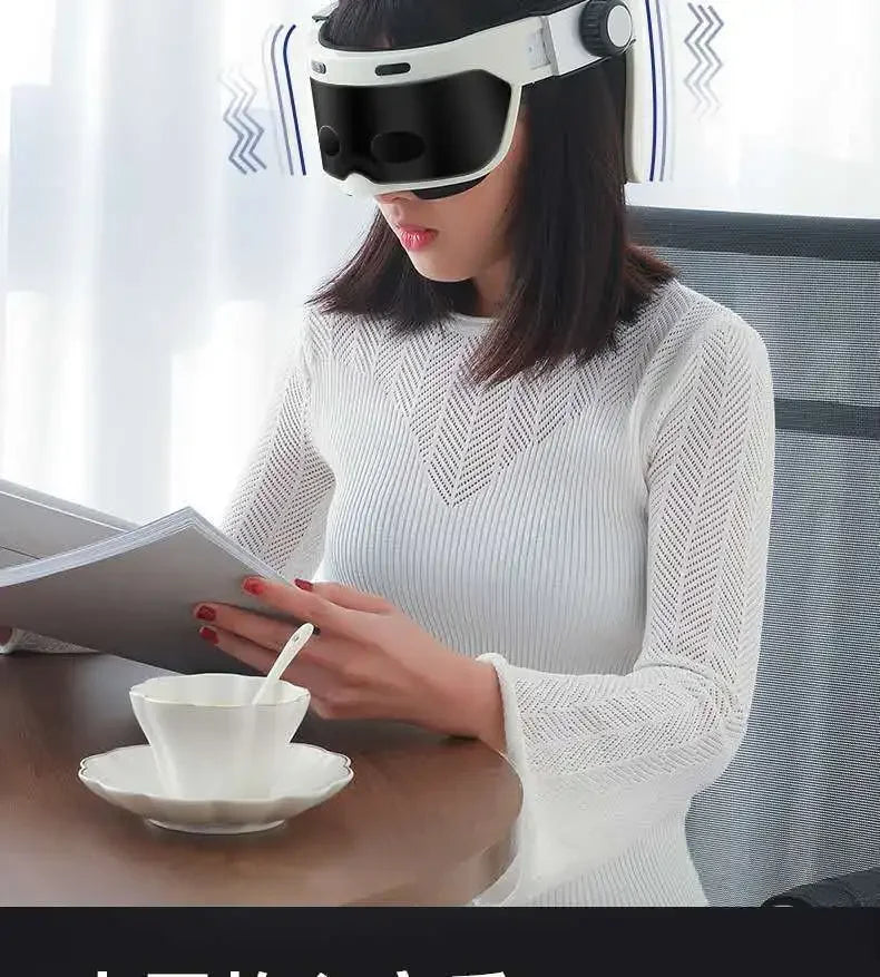Woman wearing white integrated head and eye massager helmet for relaxation and scalp therapy while reading at a table.