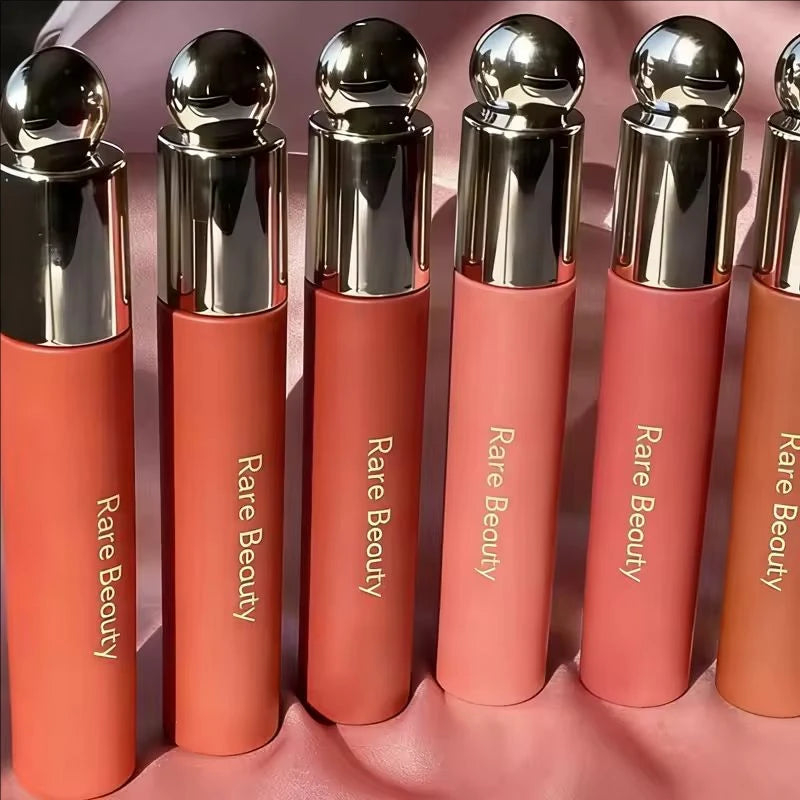 Rare Beauty Soft Pinch Tinted Lip Oil collection in various shades with matte tubes and shiny metallic gold caps.