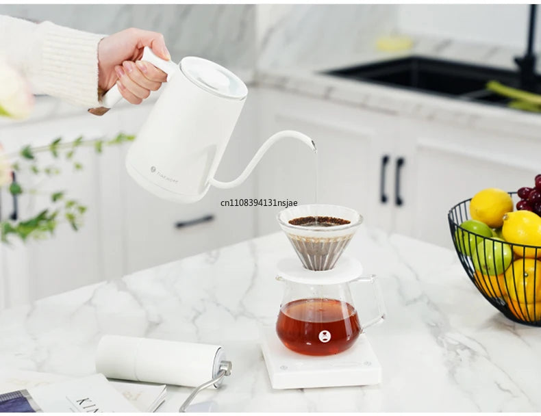 Timemore white gooseneck electric kettle pouring water into a glass pour-over coffee dripper on a kitchen counter.