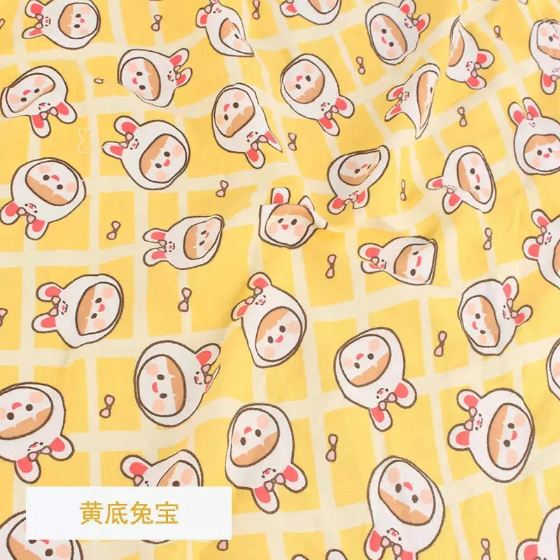 Yellow knit fabric with a white grid pattern and cute cartoon rabbit-costumed babies printed throughout.
