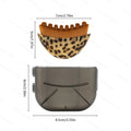 A leopard-print, semicircular facial brush with brown bristles, shown with its translucent grey storage case and sizes.