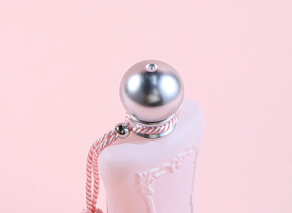 Luxury 75ml floral Eau de Parfum for women, pink bottle with silver ball cap and decorative rope detail.