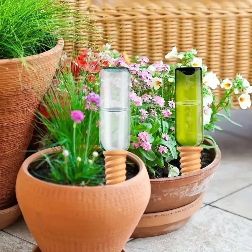 Terracotta self-watering stake with clear tube inserted in a flower pot arrangement