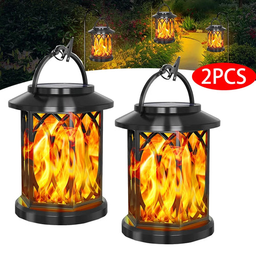 Two black solar lanterns with a flickering flame effect, hanging by clips, illuminate a garden path.