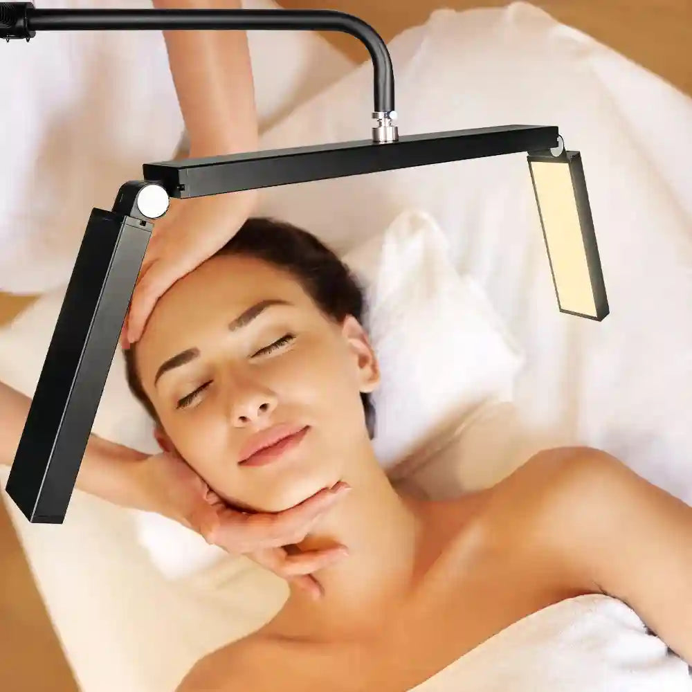 Black adjustable LED half-moon beauty lamp for esthetician treatments, positioned over a client on a massage table.