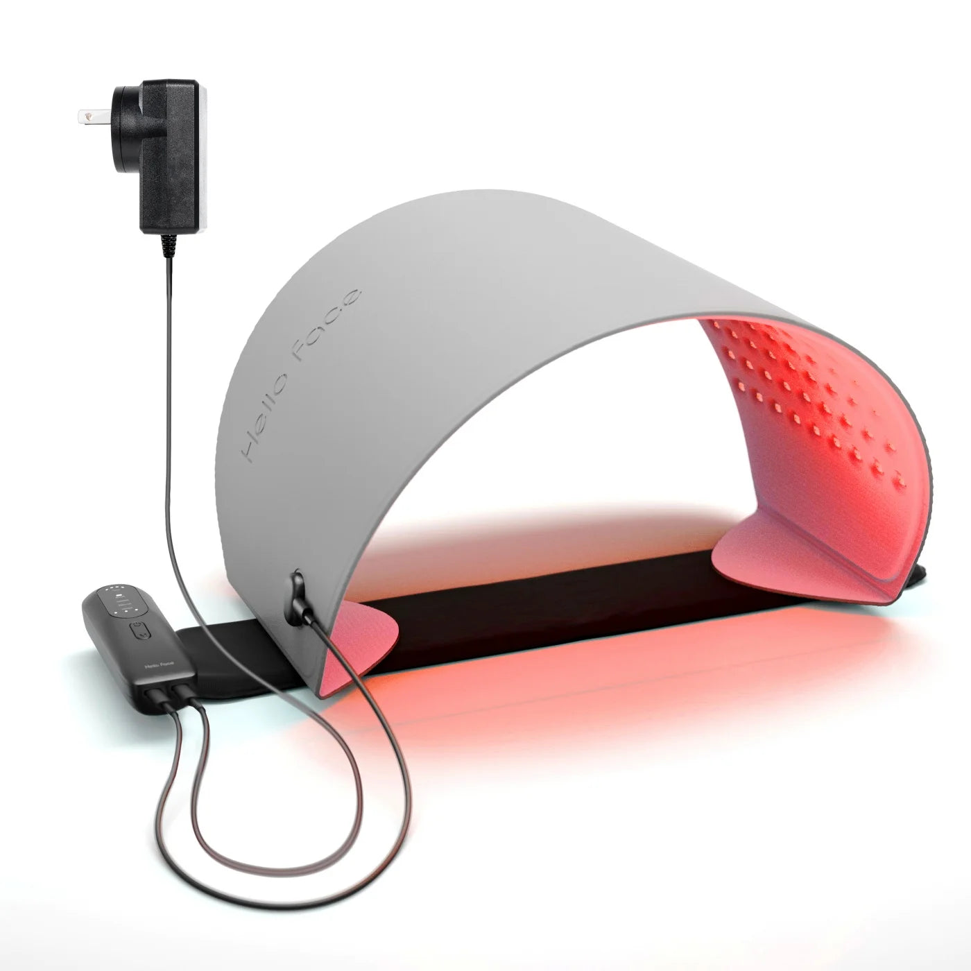 Arch-shaped grey LED light therapy mask with interior red light, plug-in power adapter, and remote control unit.