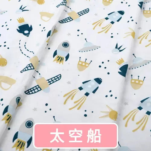 White organic knit fabric with a playful blue and yellow space print featuring rockets, satellites, and flying saucers.