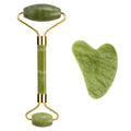 Green jade face roller and heart-shaped gua sha scraper tool with gold metal accents on a white background.