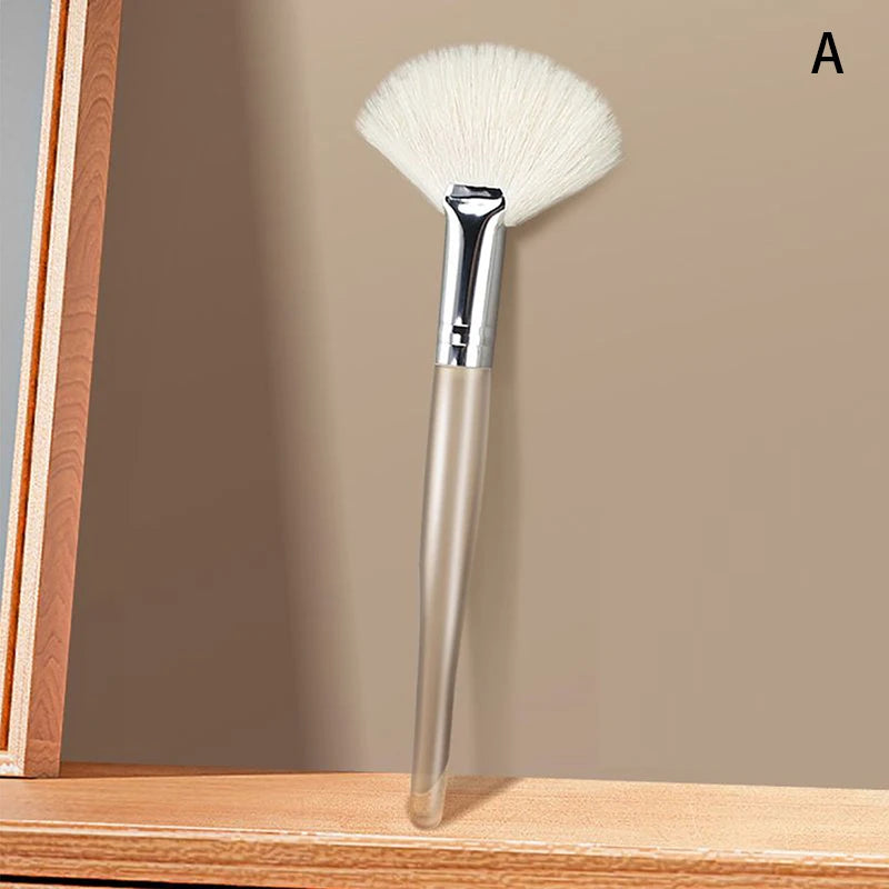 Soft fan-shaped facial mask brush with white synthetic bristles and a sleek, clear handle for skincare application.