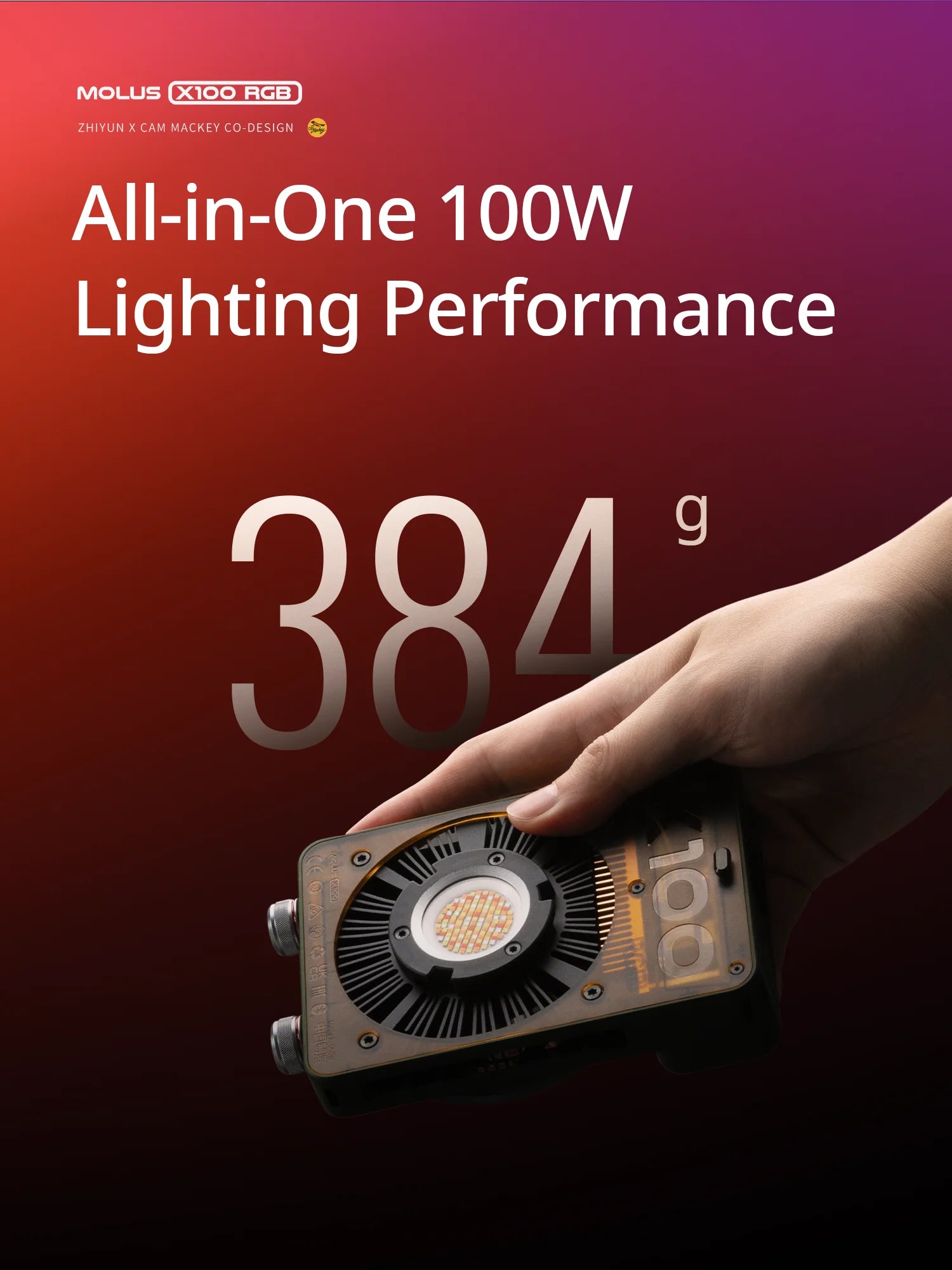 Molus X100 RGB compact 100W LED video light with a translucent black casing, held in a hand to show its small size.