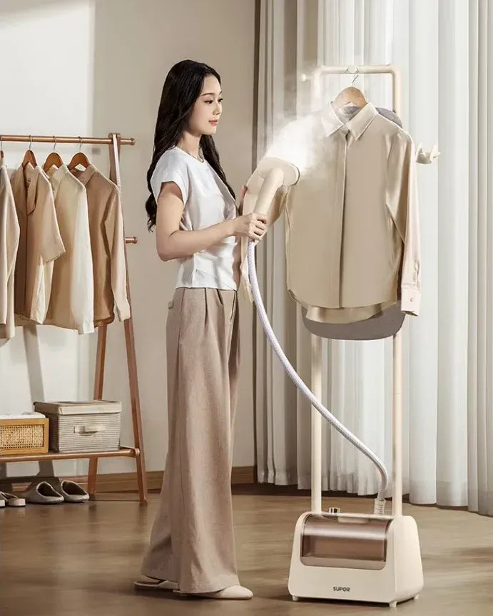 Garment steamer removes wrinkles easily from a hanging beige shirt on a standing fabric steamer rack.