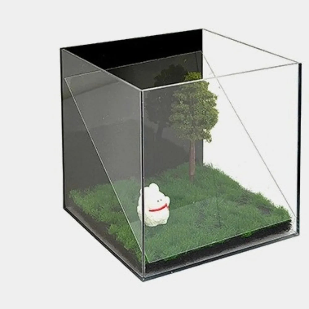 Clear acrylic holographic pet projection box for 3D digital pet souvenirs and display in a grassy landscape setting.