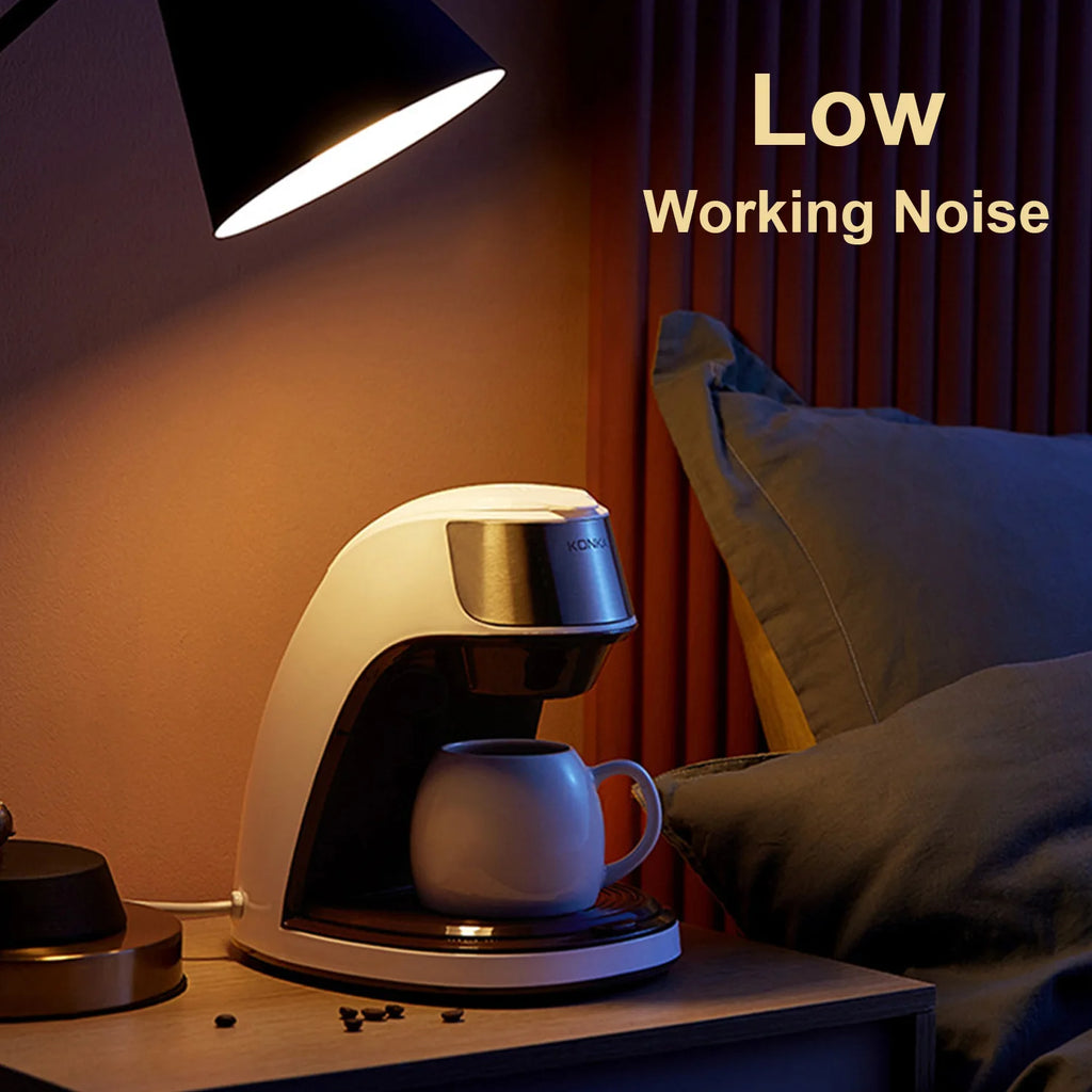 Konka white compact single-serve coffee maker with silver accents on a nightstand for quiet bedside brewing.